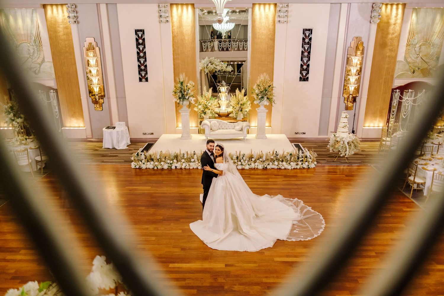 Elegant bridal portraits in a luxurious ballroom with ornate gold decor and warm wooden floors.