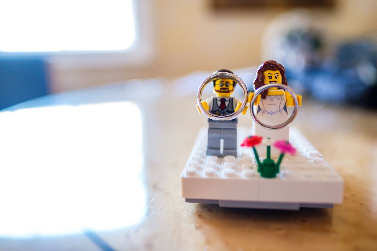 Small LEGO minifigures arranged on a wooden surface in soft natural lighting.