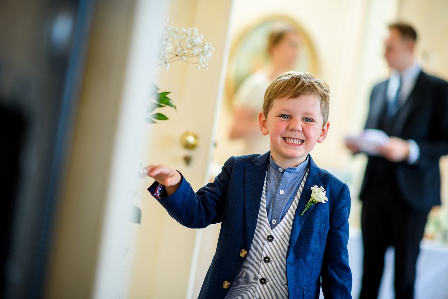 Wedding guests gather in an elegant room with chandeliers and light decor.