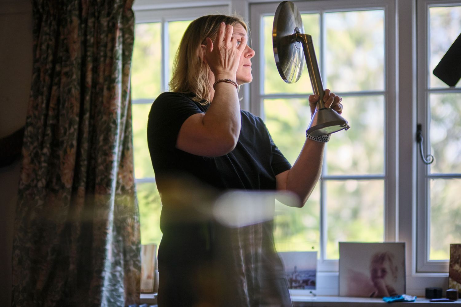A person wipes a window with a cloth in a sequence of cleaning motions against sunlit glass.