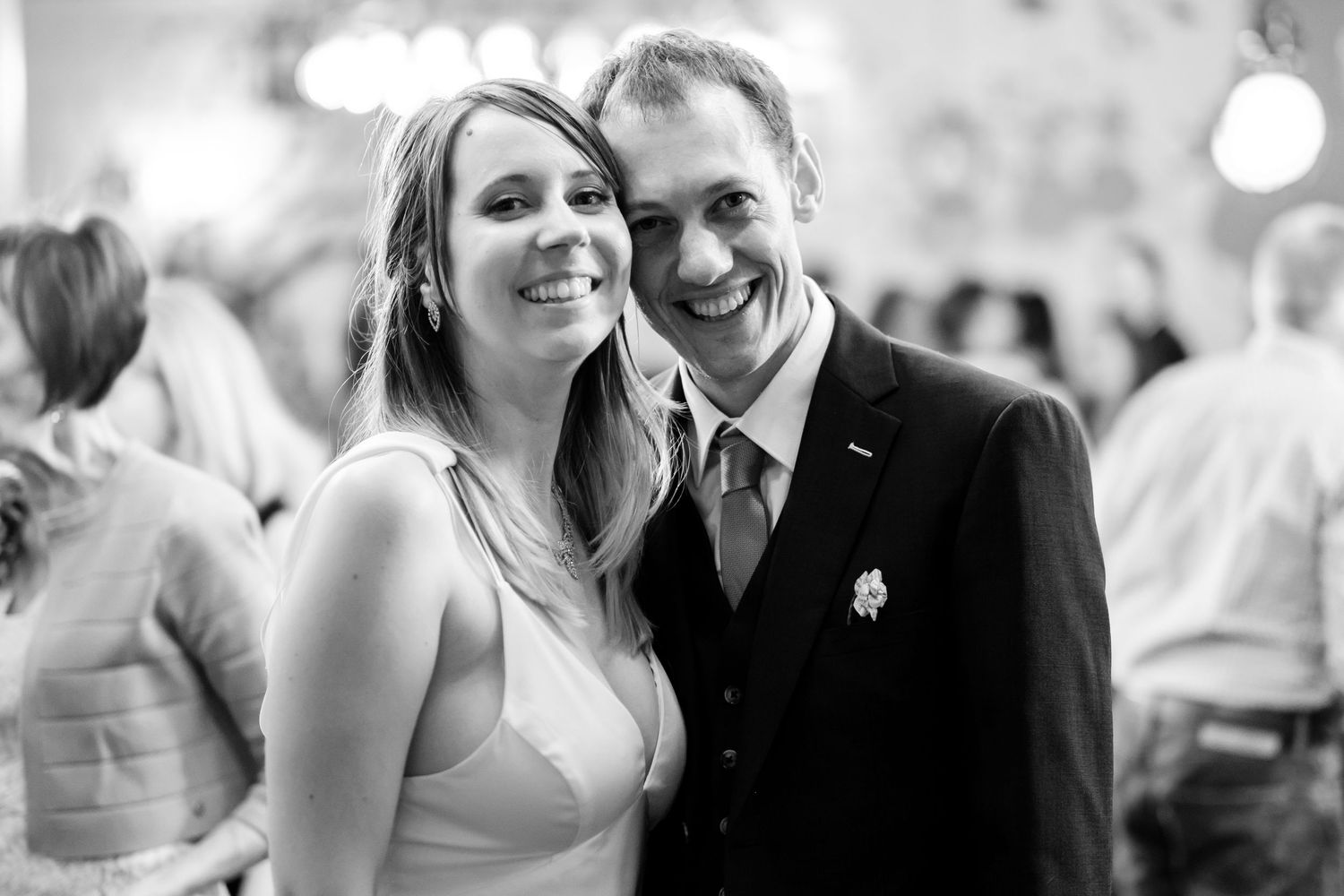 Happy couple shares intimate moment during wedding reception in black and white photo.