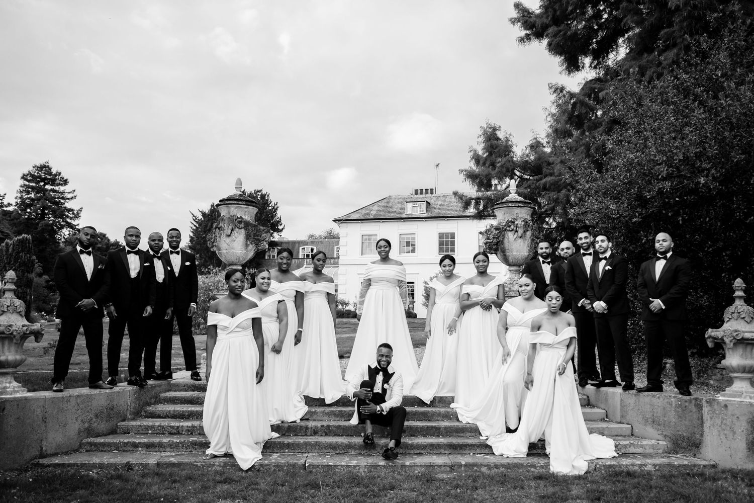 A black and white panoramic shot of a wedding party on elegant stone steps.