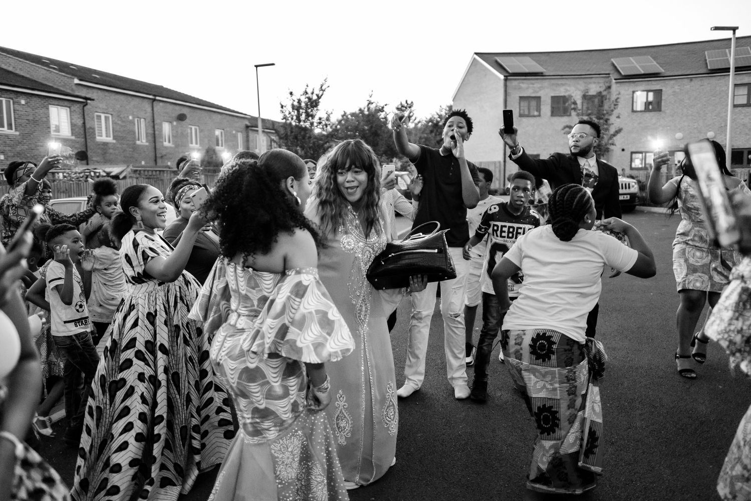 Large outdoor group celebration with people dancing and moving in a line formation.