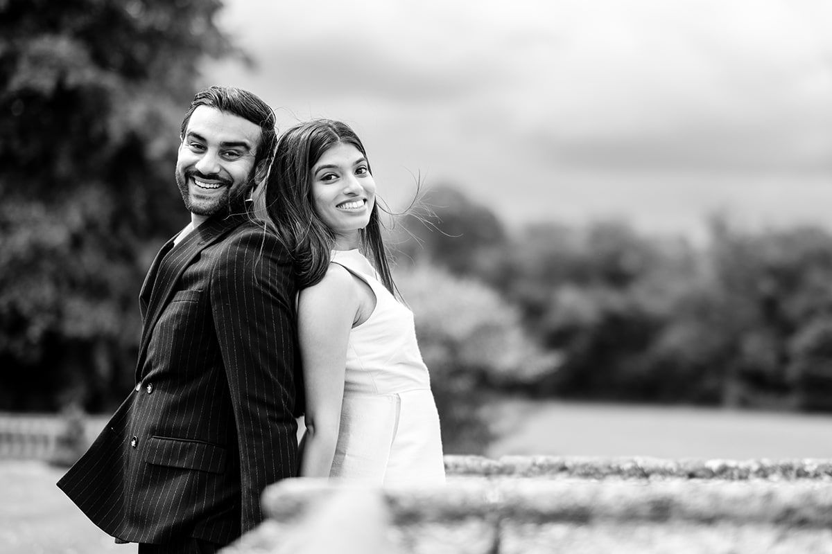 Black and white portrait of couple standing back-to-back in classic wedding attire.