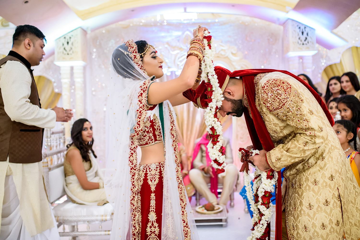 Traditional Indian wedding ceremony with guests in colorful attire celebrating indoors.