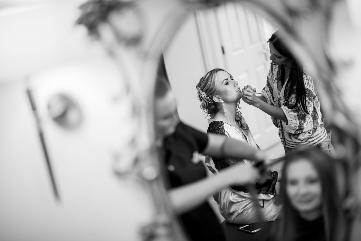 Candid moments captured during wedding preparation with natural window lighting.
