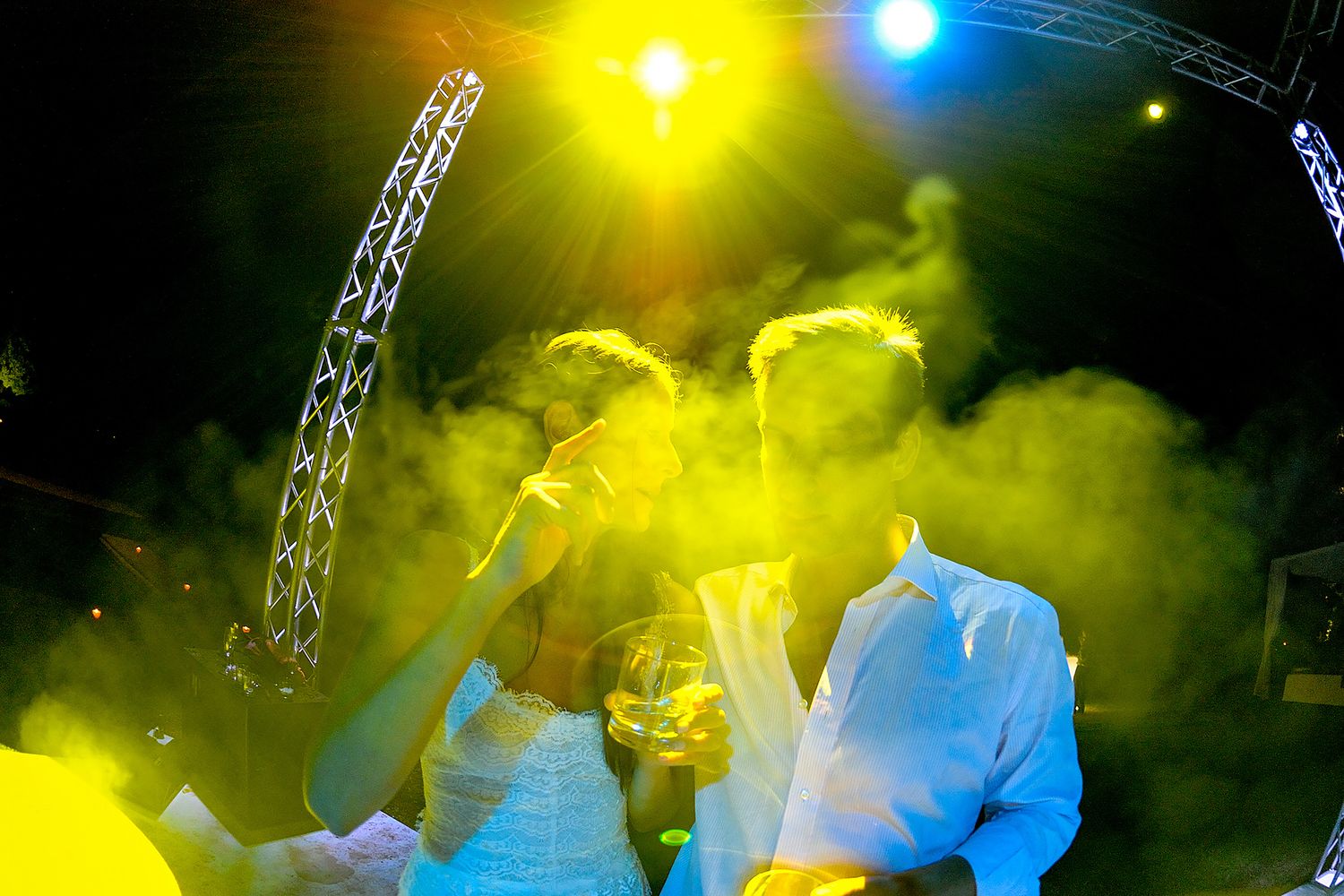 Concert performance with dramatic yellow and blue lighting effects and fog machine atmosphere.