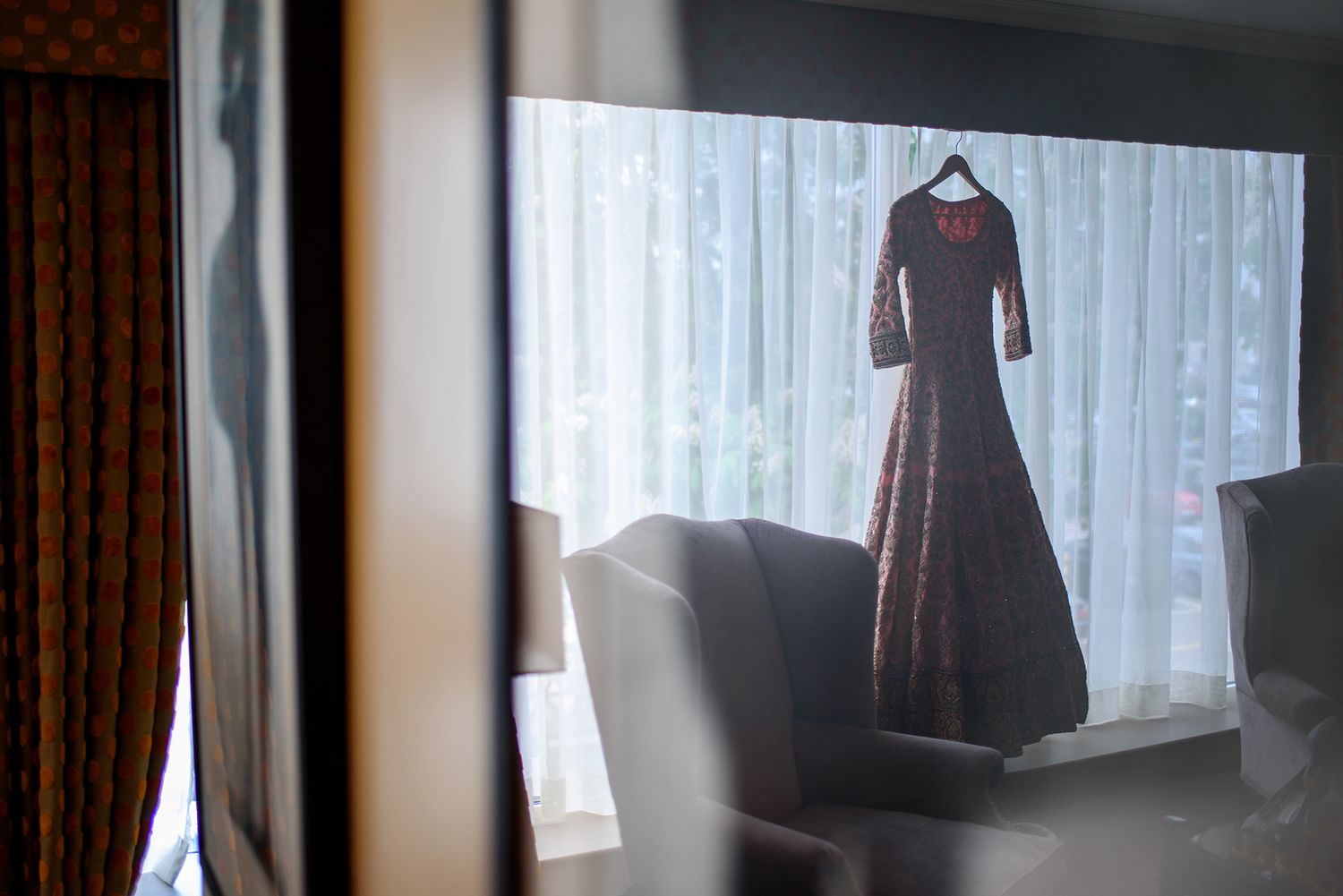 Elegant formal dress hanging by window with soft natural lighting.
