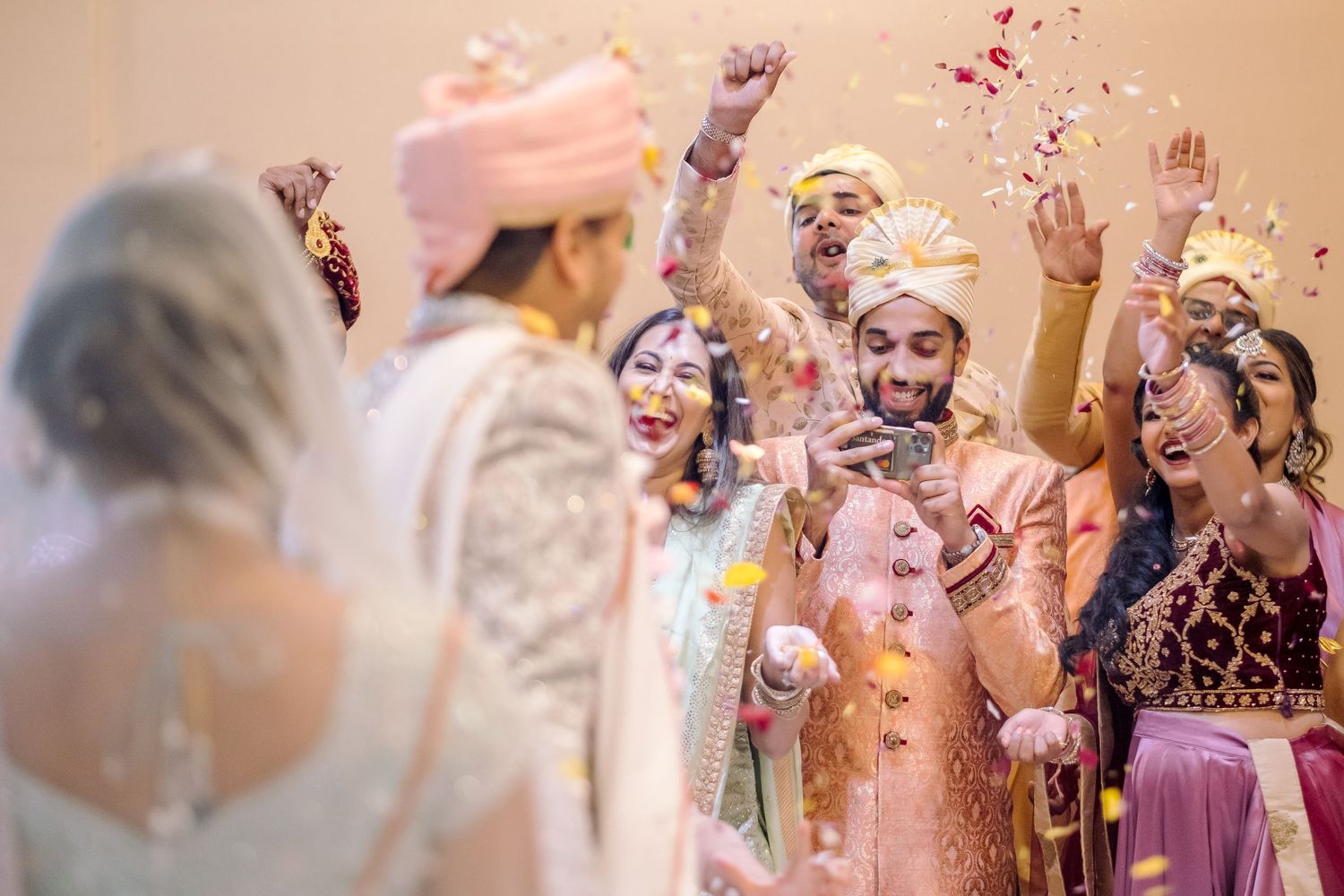 Wedding celebration with guests throwing confetti and rose petals during a joyous moment.
