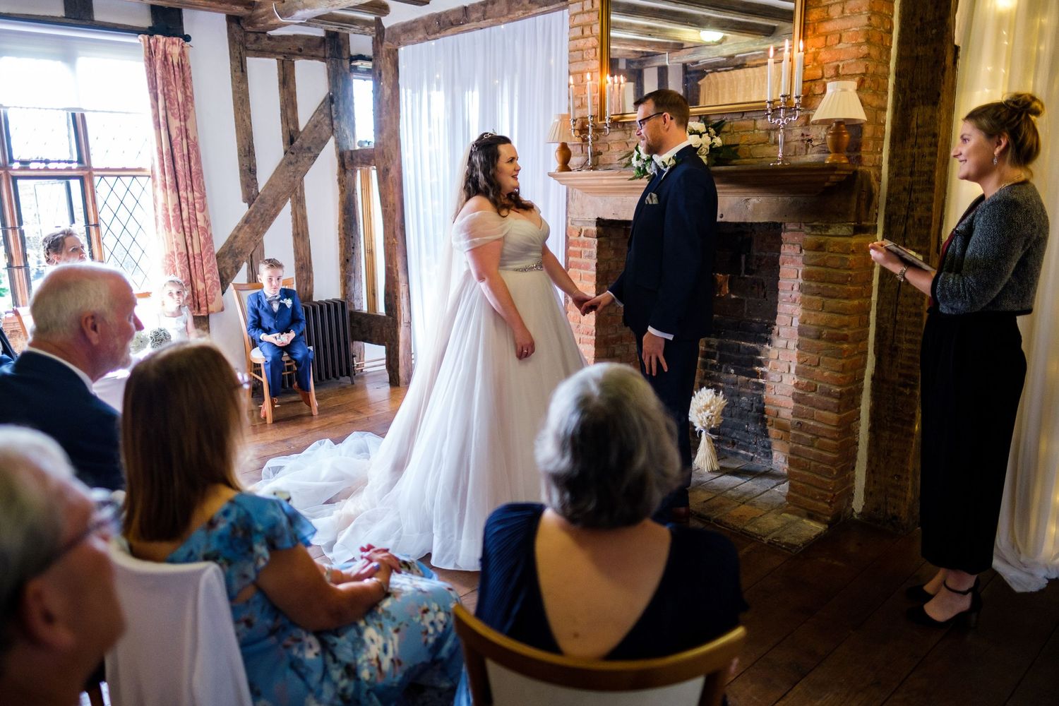 Wedding ceremony in progress inside historic brick building with exposed beams.