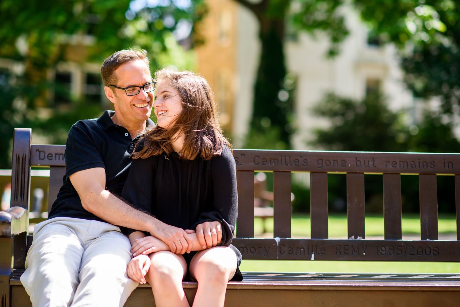 Romantic couple shares tender moments together on a wooden park bench surrounded by greenery.
