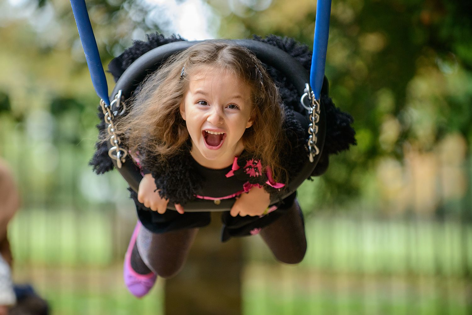 A joyful child swings high in the air at a playground on a sunny day.
