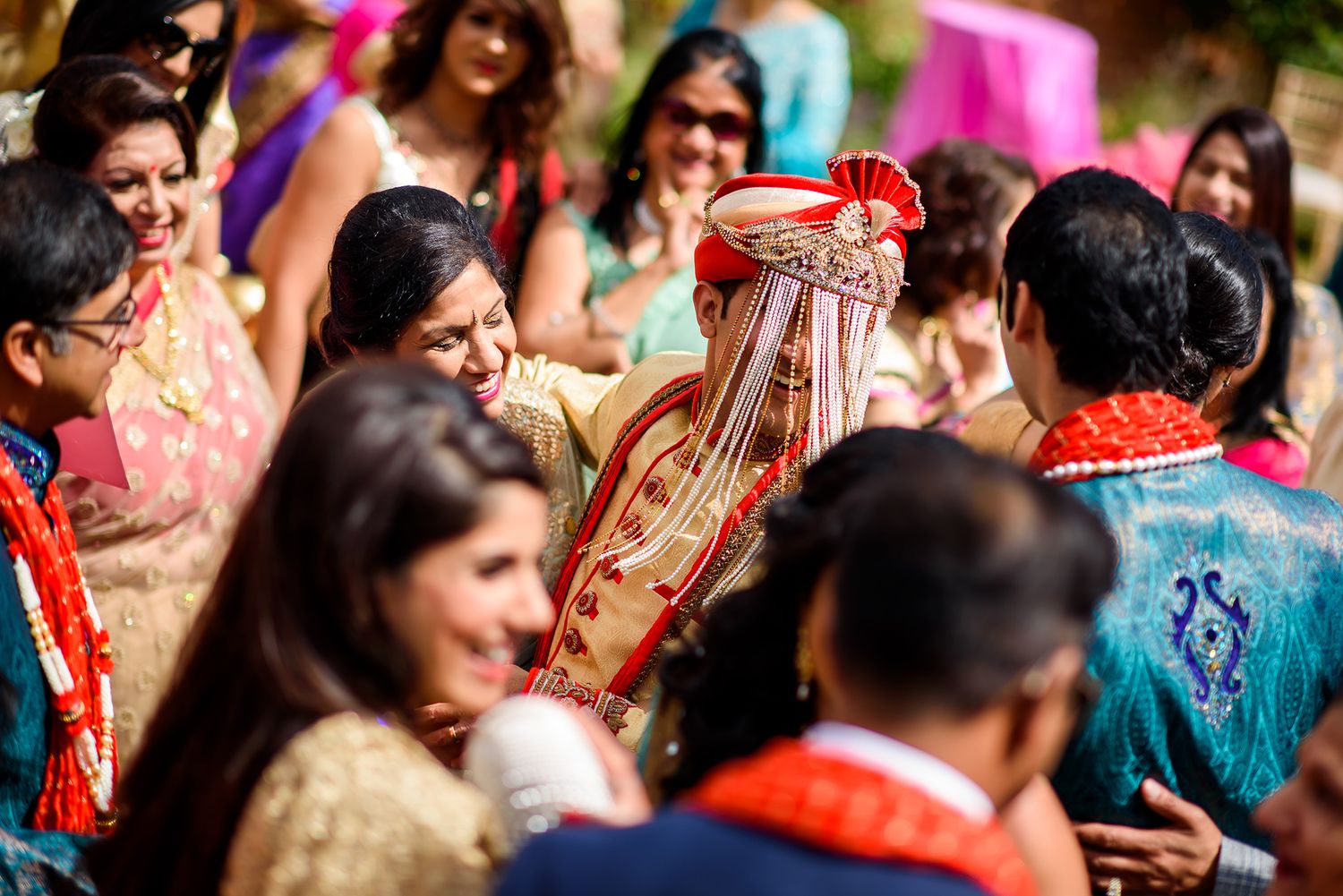 Colorful traditional Indian wedding ceremony with guests wearing vibrant saris and traditional attire.