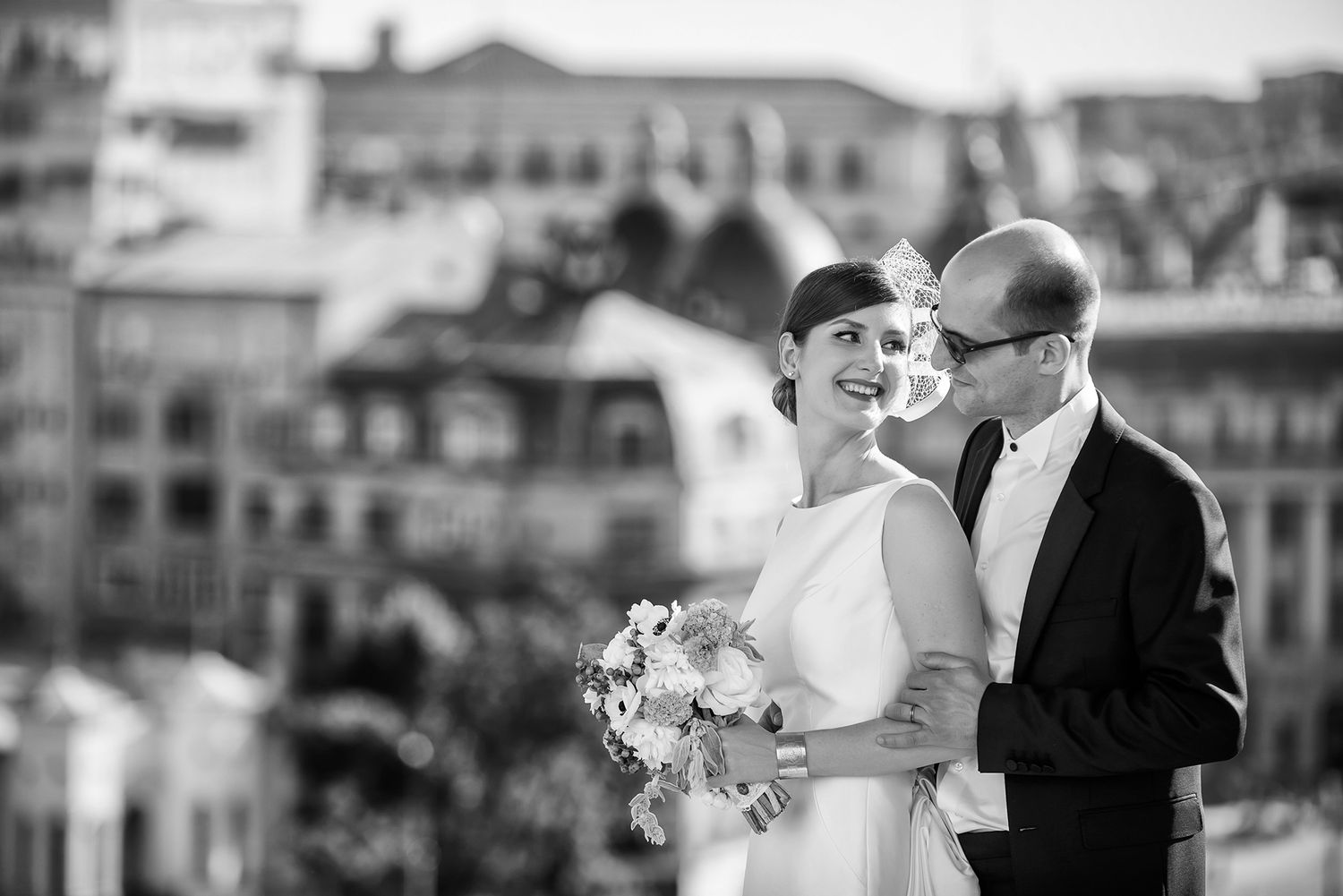 Romantic wedding moment captured against an urban city backdrop with classic architecture.