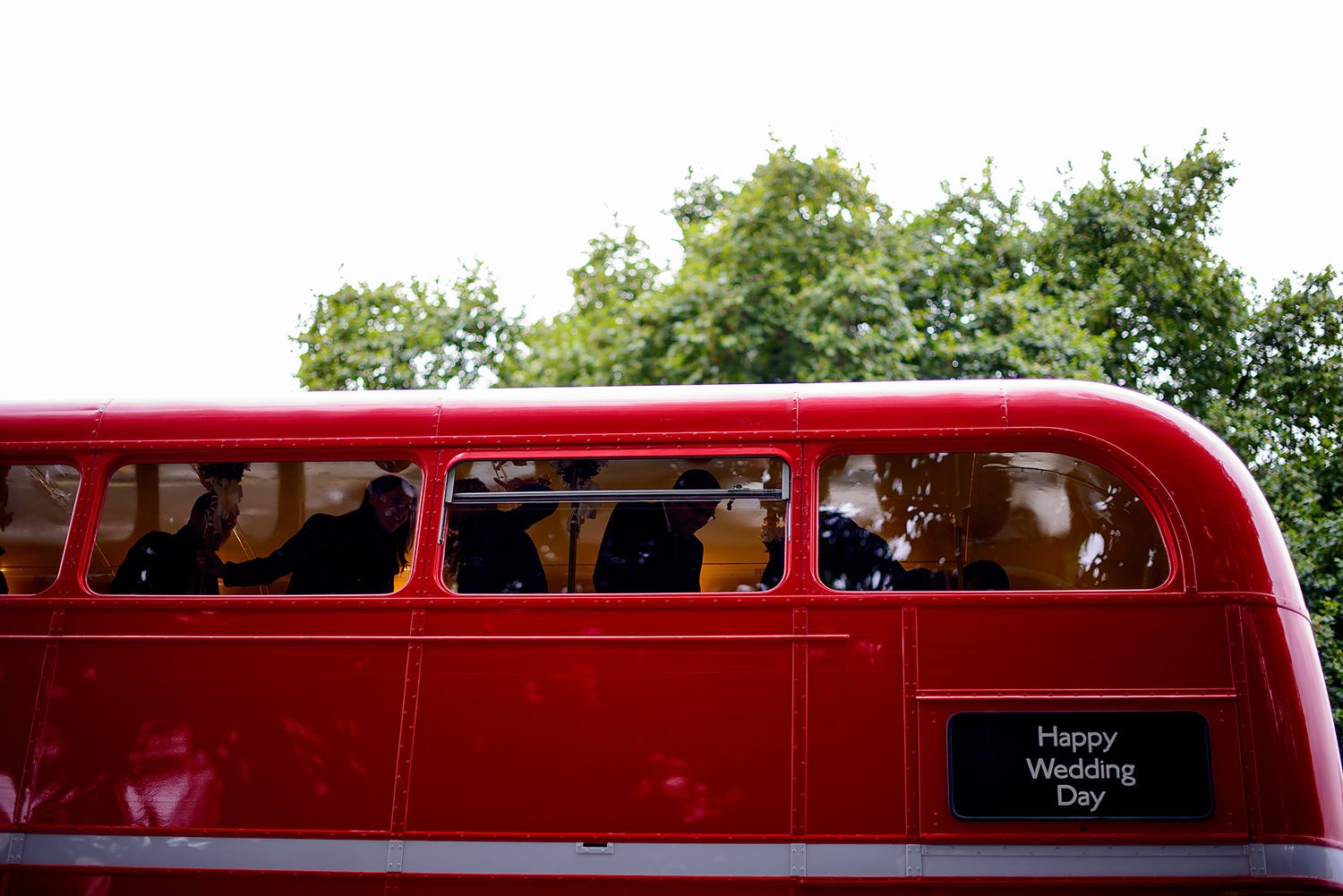 Classic red vintage wedding bus transports celebration party through London streets.