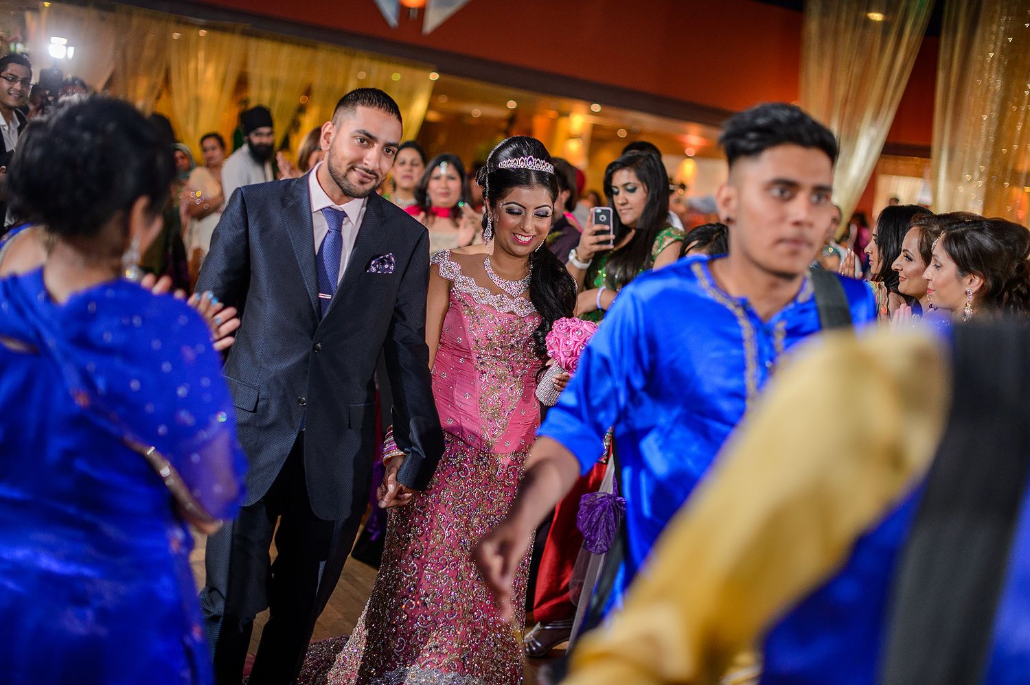 Vibrant celebration with guests dancing under warm lighting at an elegant venue.