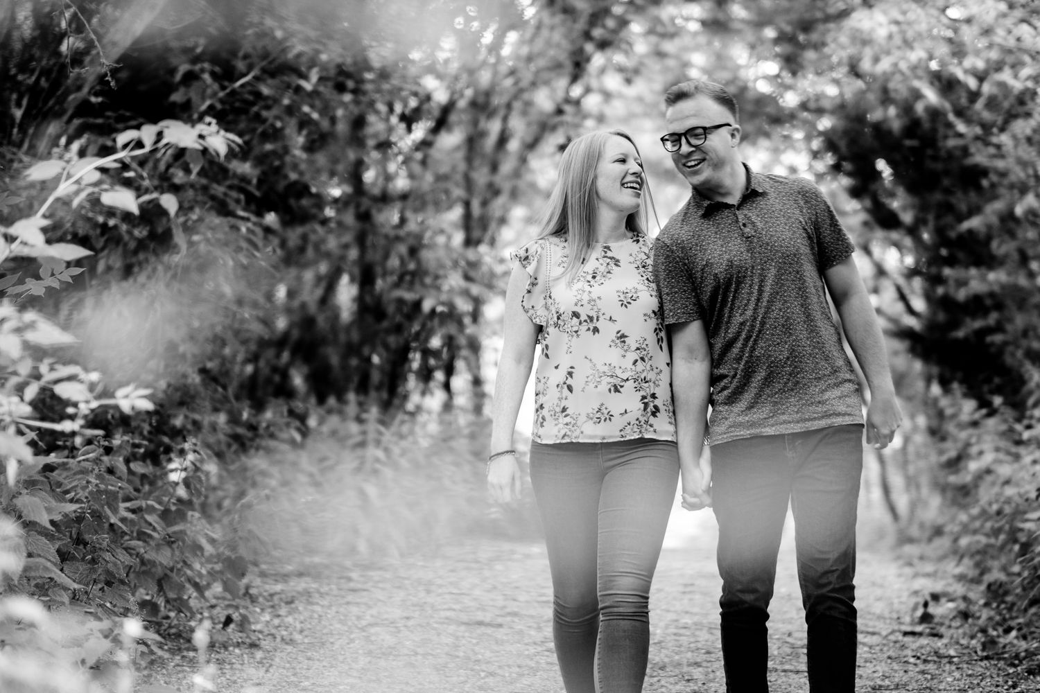 Black and white photo captures candid walking moment between wedding guests in nature.