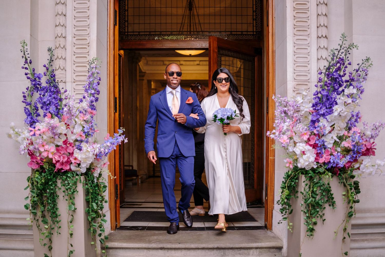 Wedding venue entrance decorated with cascading purple and pink floral arrangements.