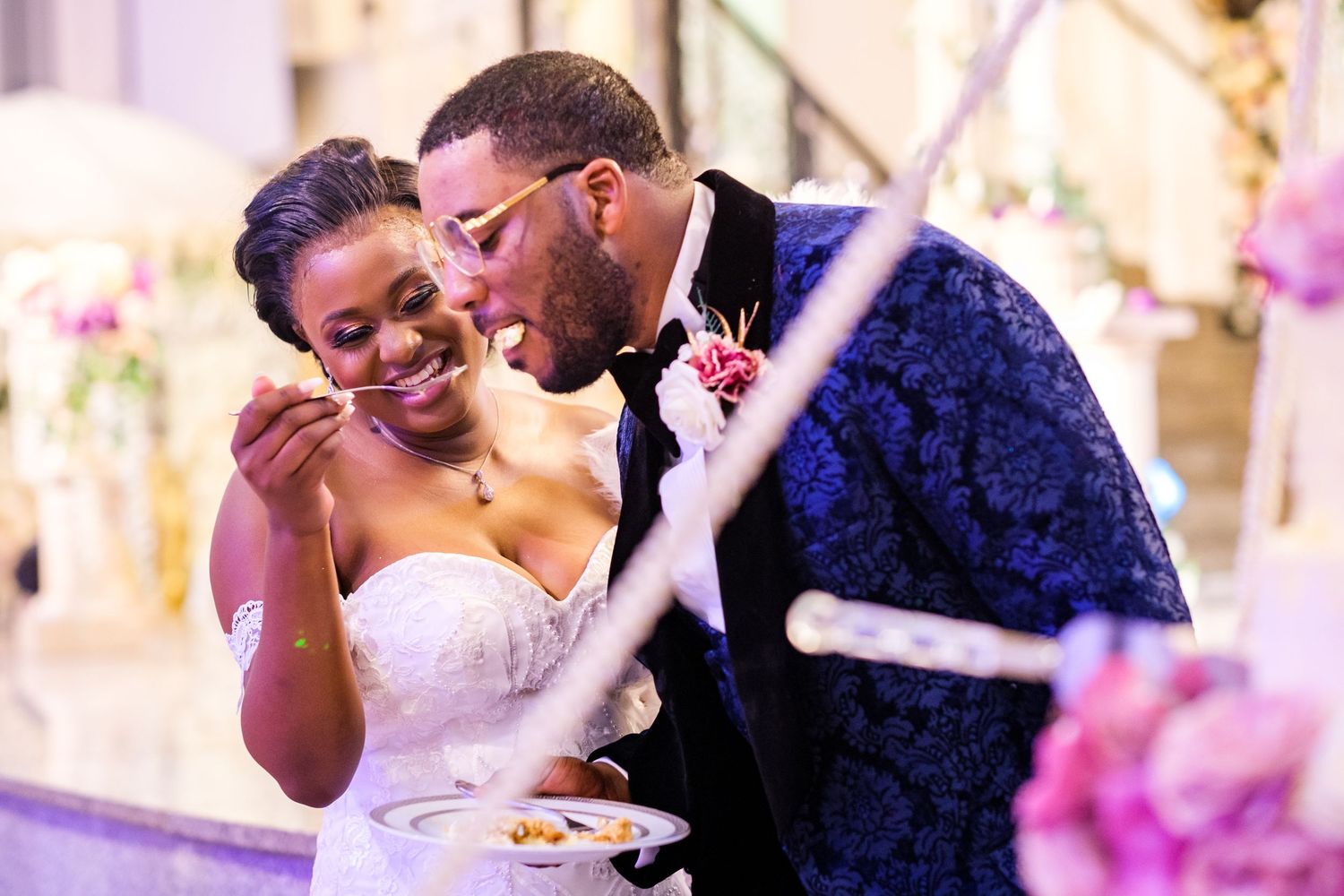 Newlyweds sharing a sweet moment during wedding reception cake cutting.