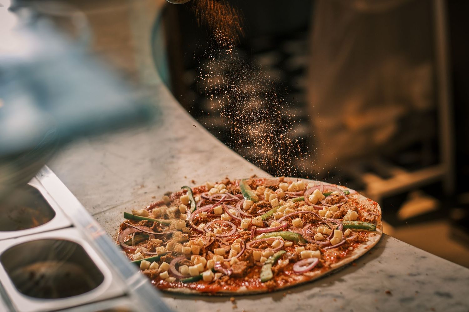 Freshly baked pizza with toppings on a wooden serving board in dim lighting.