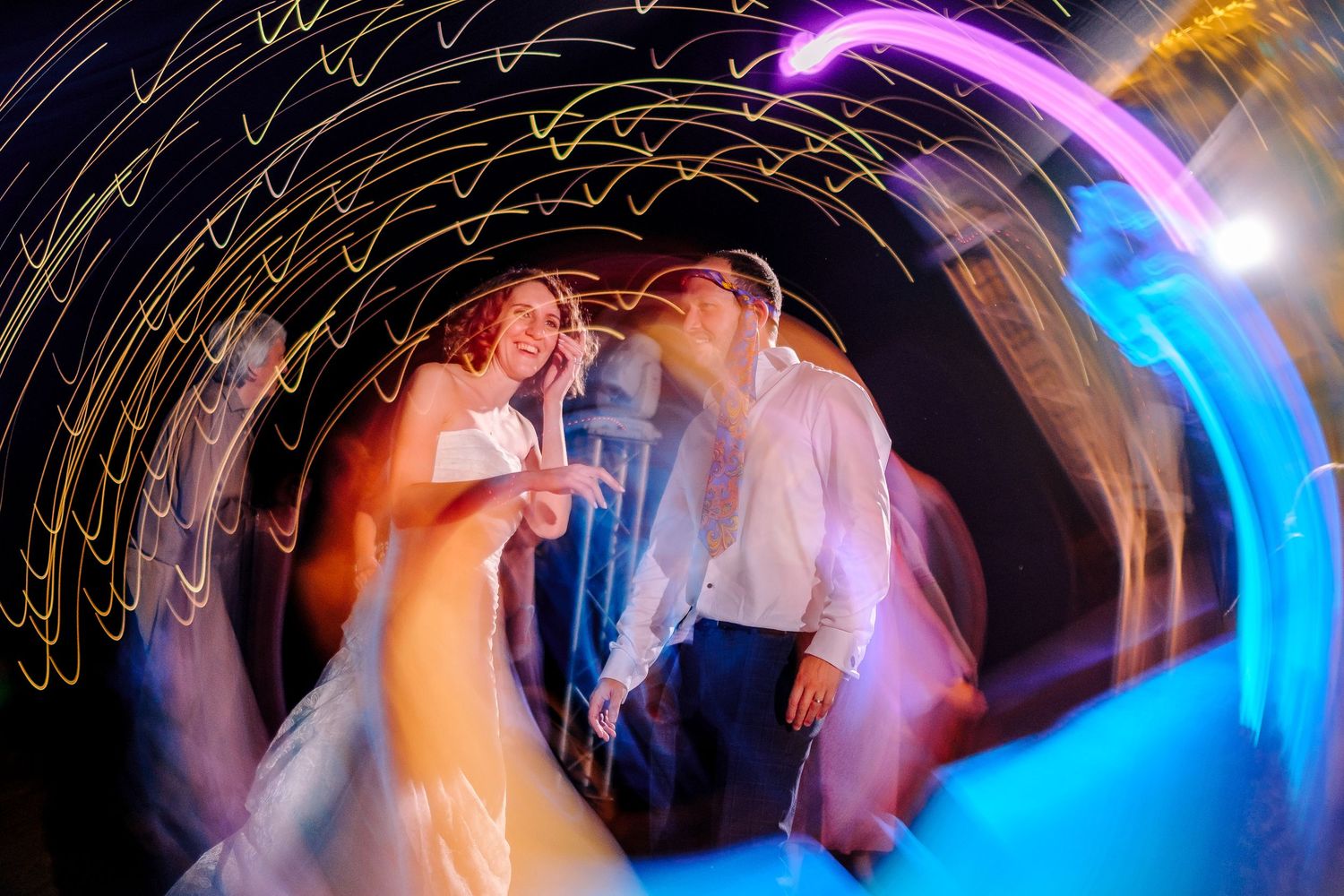 A dynamic nighttime dance photo with light trails and colorful illumination creating an artistic swirl effect.