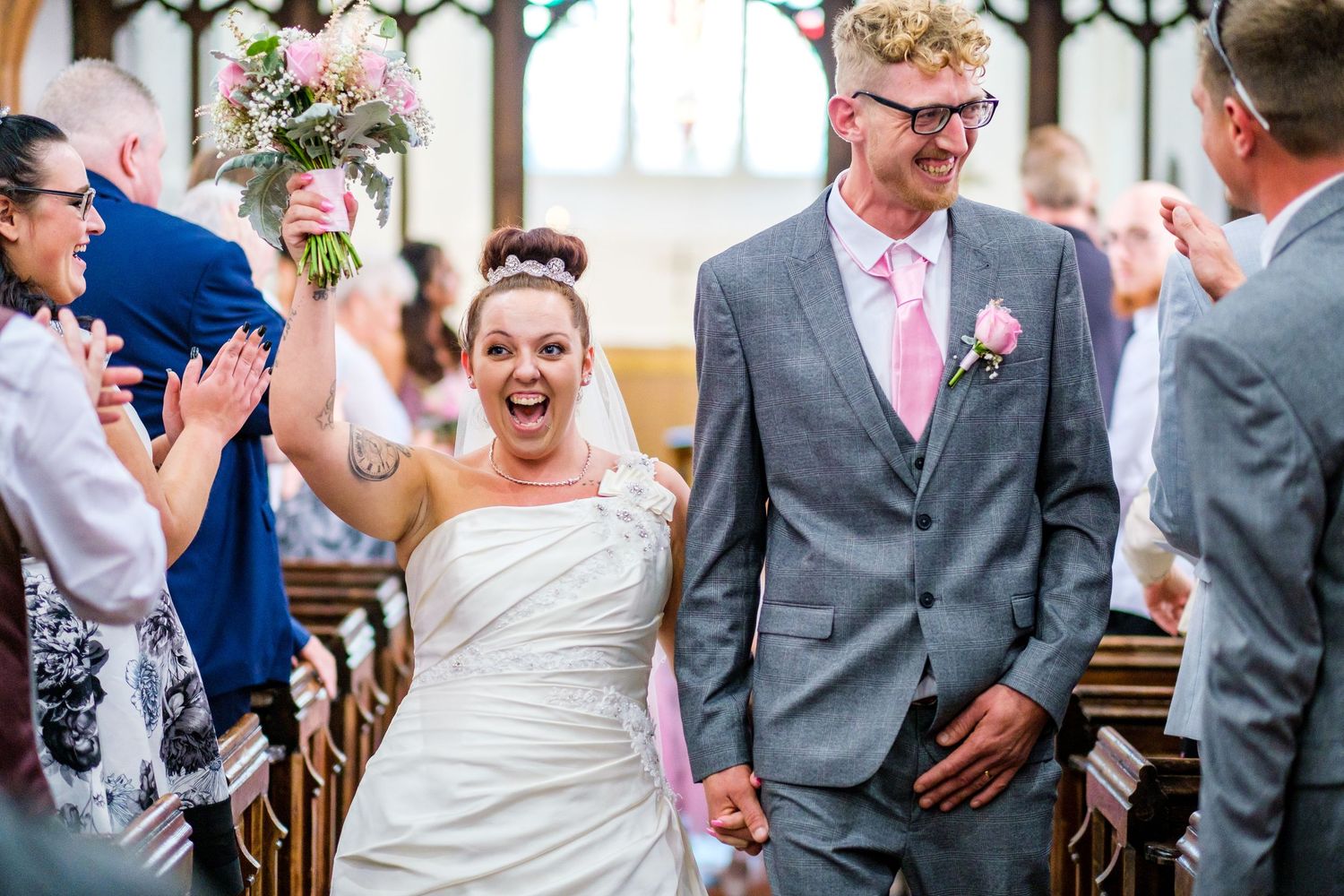 Wedding party celebrating in a church with joyful expressions and formal attire.