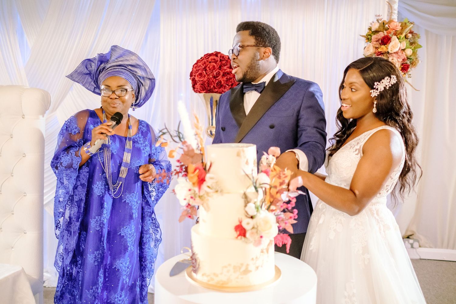 Wedding celebration with guests in traditional attire dancing and mingling in a white-draped venue.