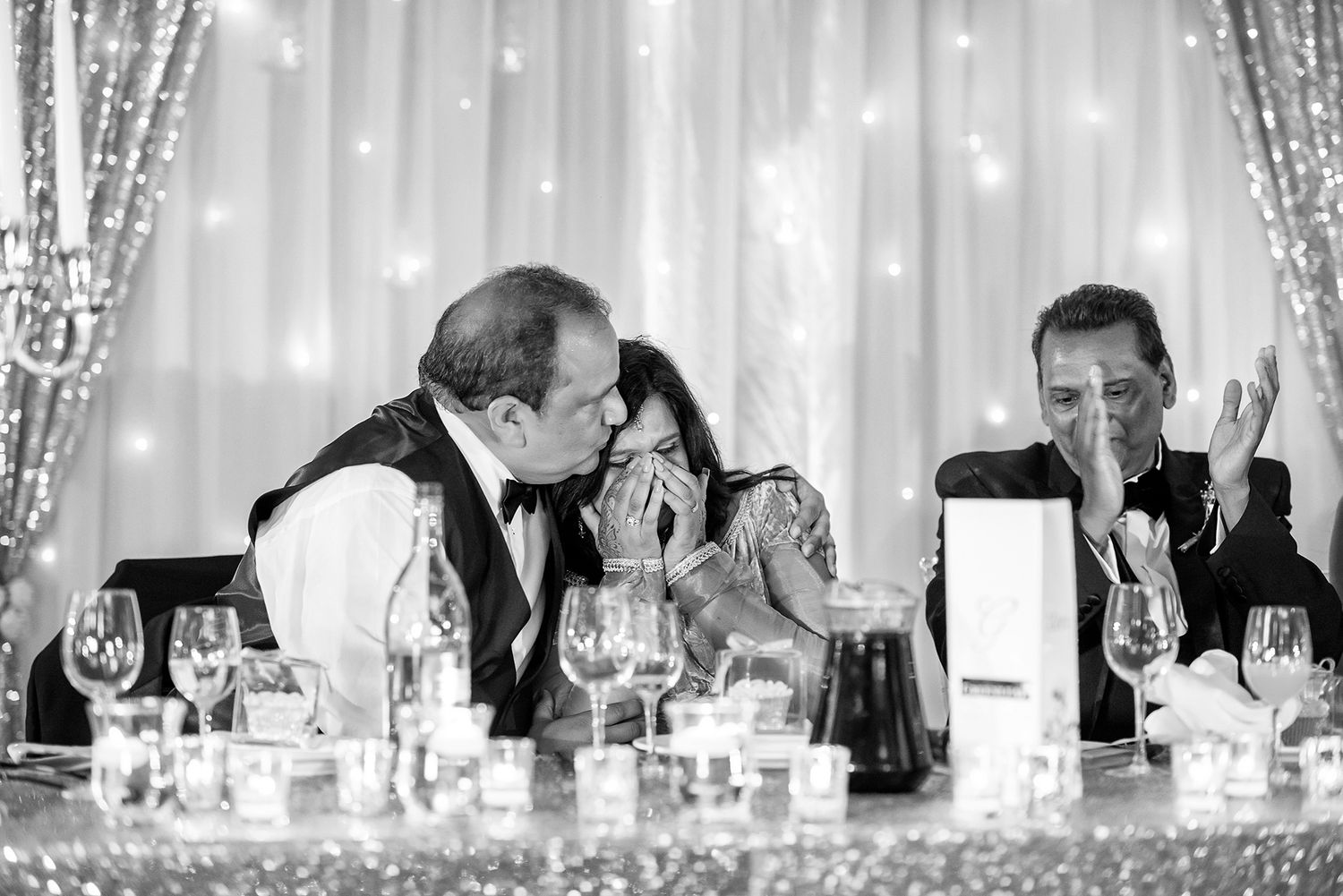 Black and white photo of an elegant wedding reception with candelabras and formal table settings.