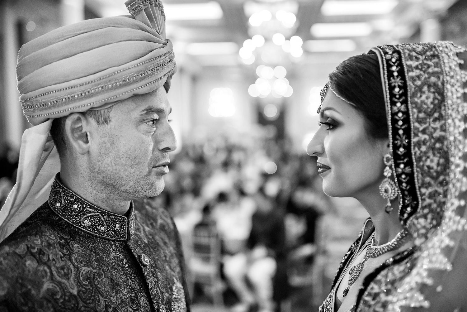 Black and white portrait of a couple in traditional South Asian wedding attire.