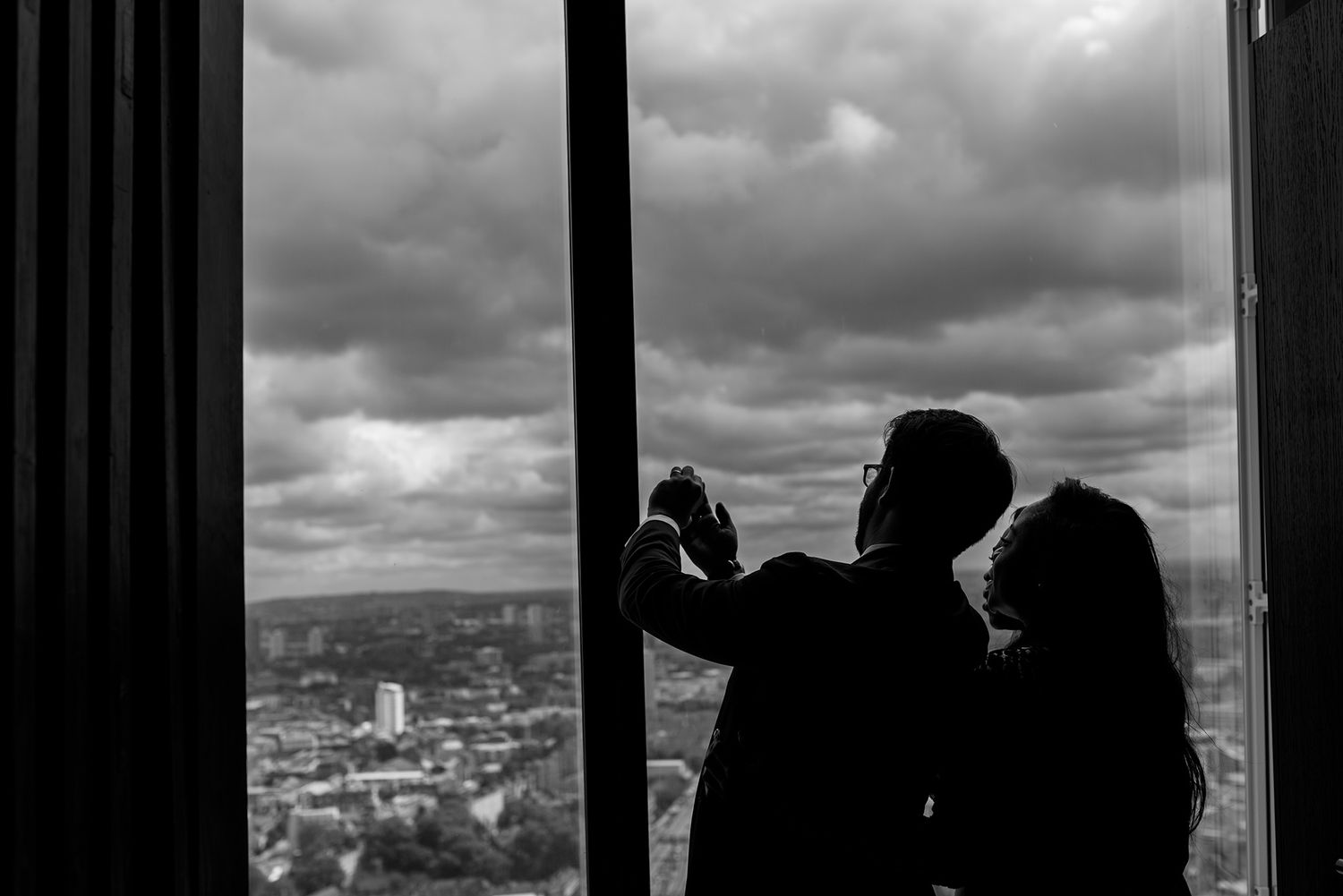 Dramatic silhouettes against cityscape view through large windows.