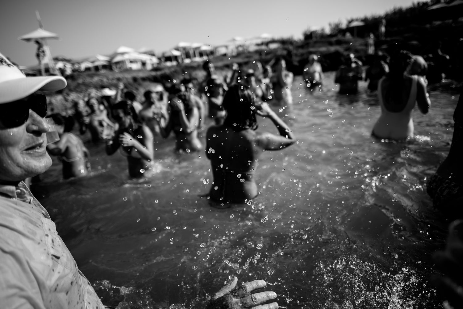 Joyful crowd splashes in water during an outdoor summer celebration.