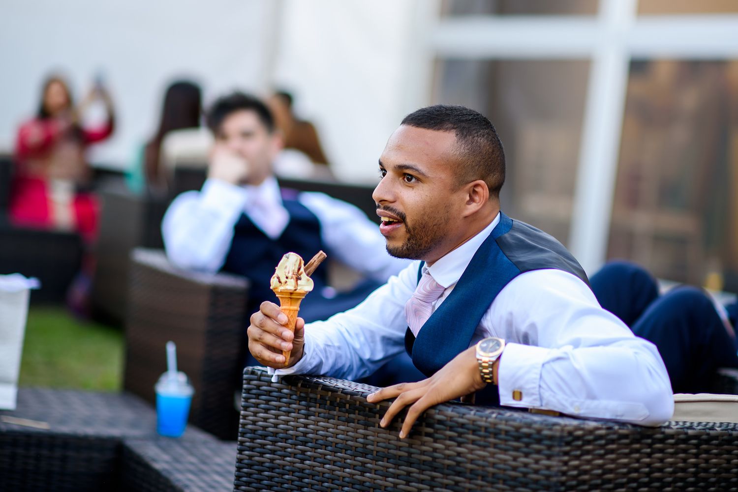 Outdoor wedding reception with guests relaxing on patio furniture.