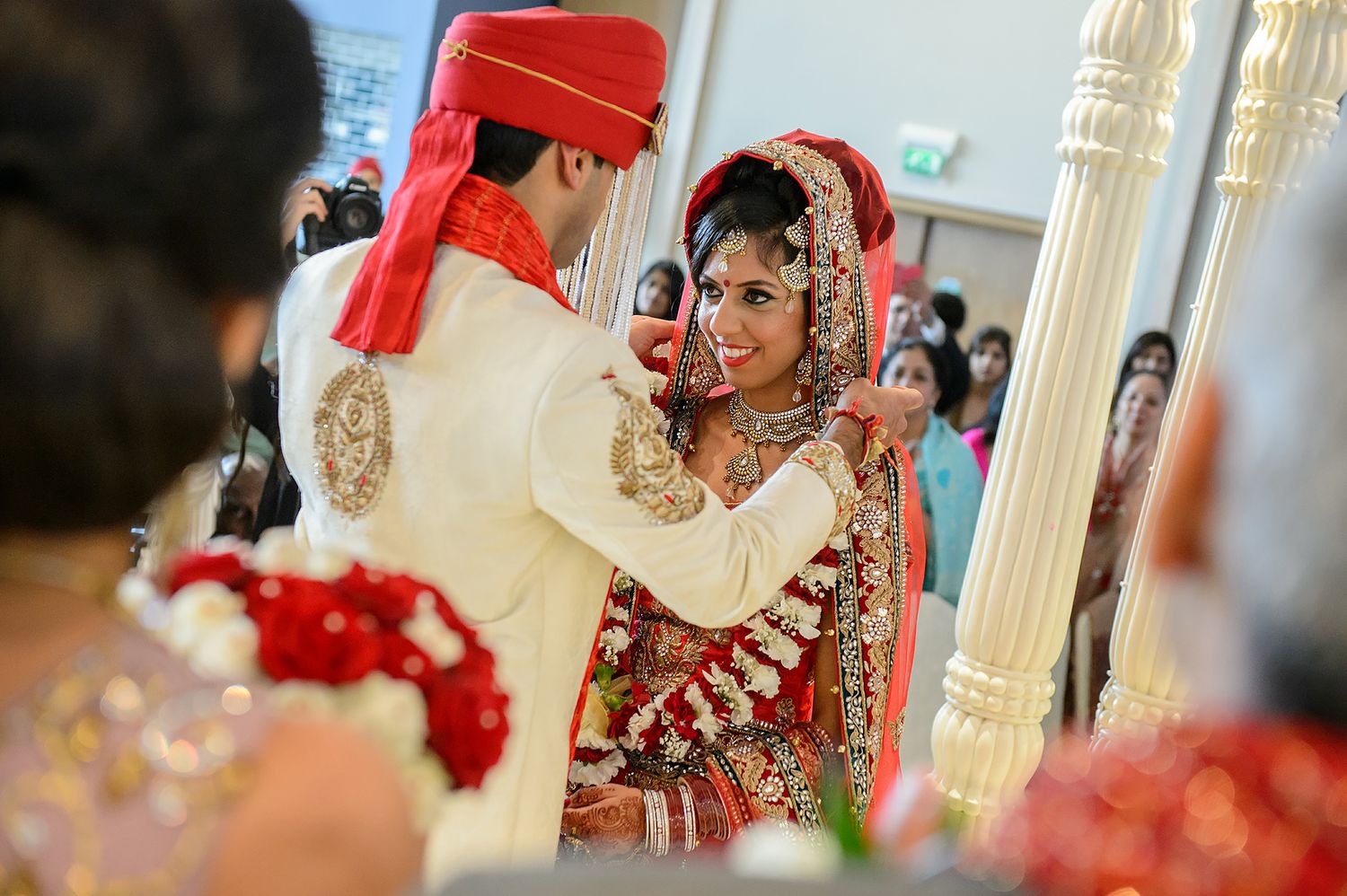 Traditional Indian wedding ceremony decorations with red and gold accents in an elegant indoor venue.