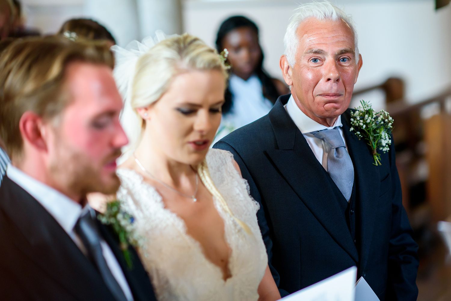 Close up photo of a wedding ceremony with people smiling during an intimate indoor moment.