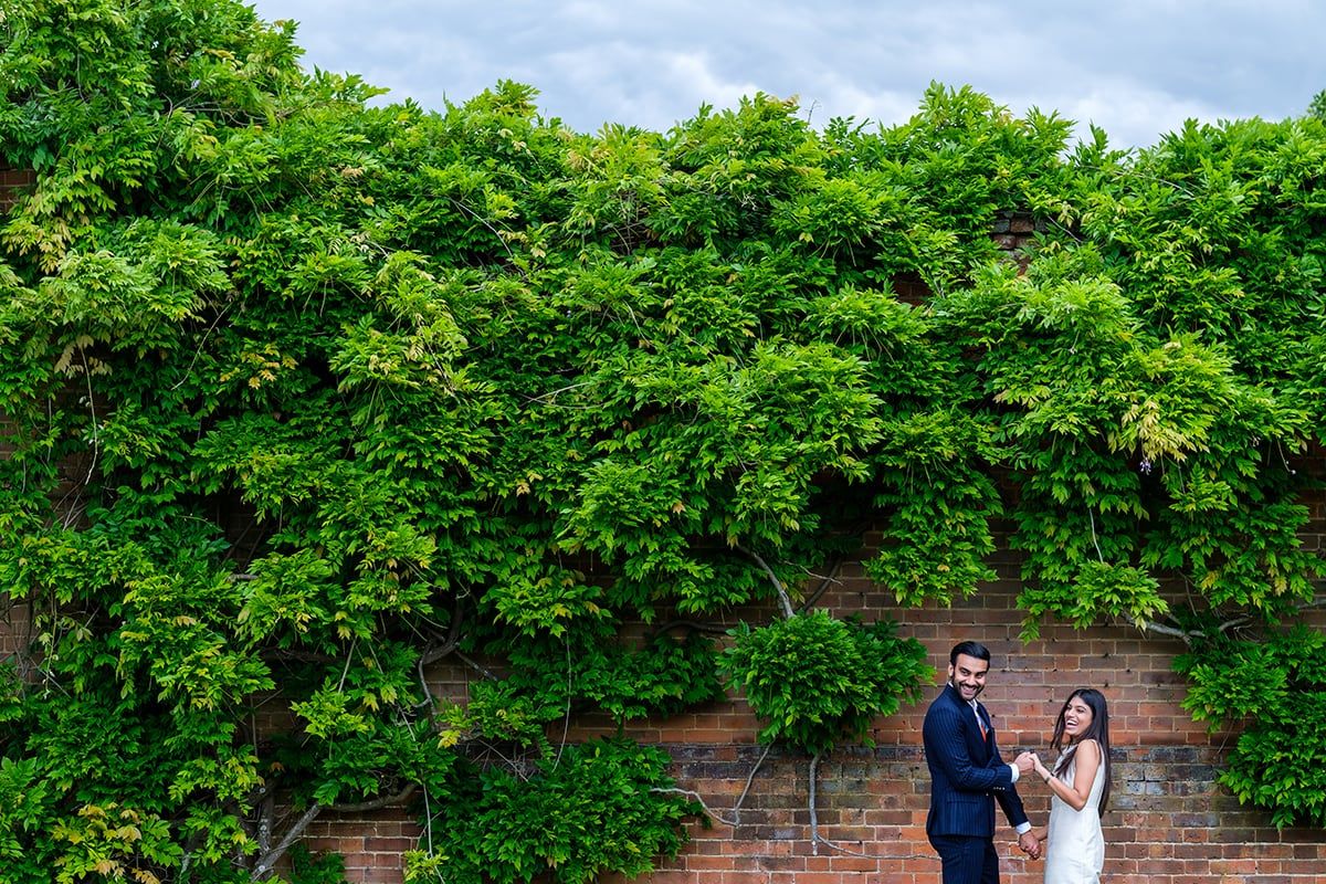 A lush green garden wall provides a natural backdrop along a brick pathway.
