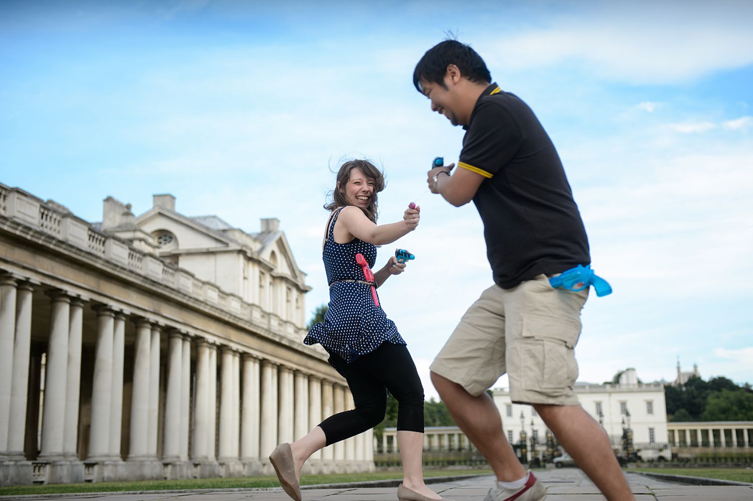 Playful moment captured between two people dancing in front of a columned building.
