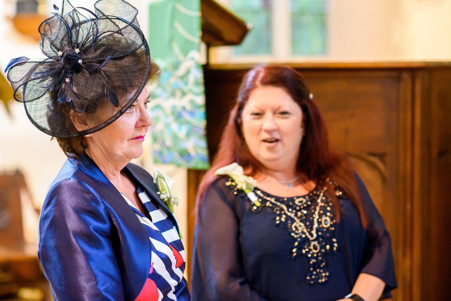 Wedding guests in formal attire with decorative hats enjoying the celebration.