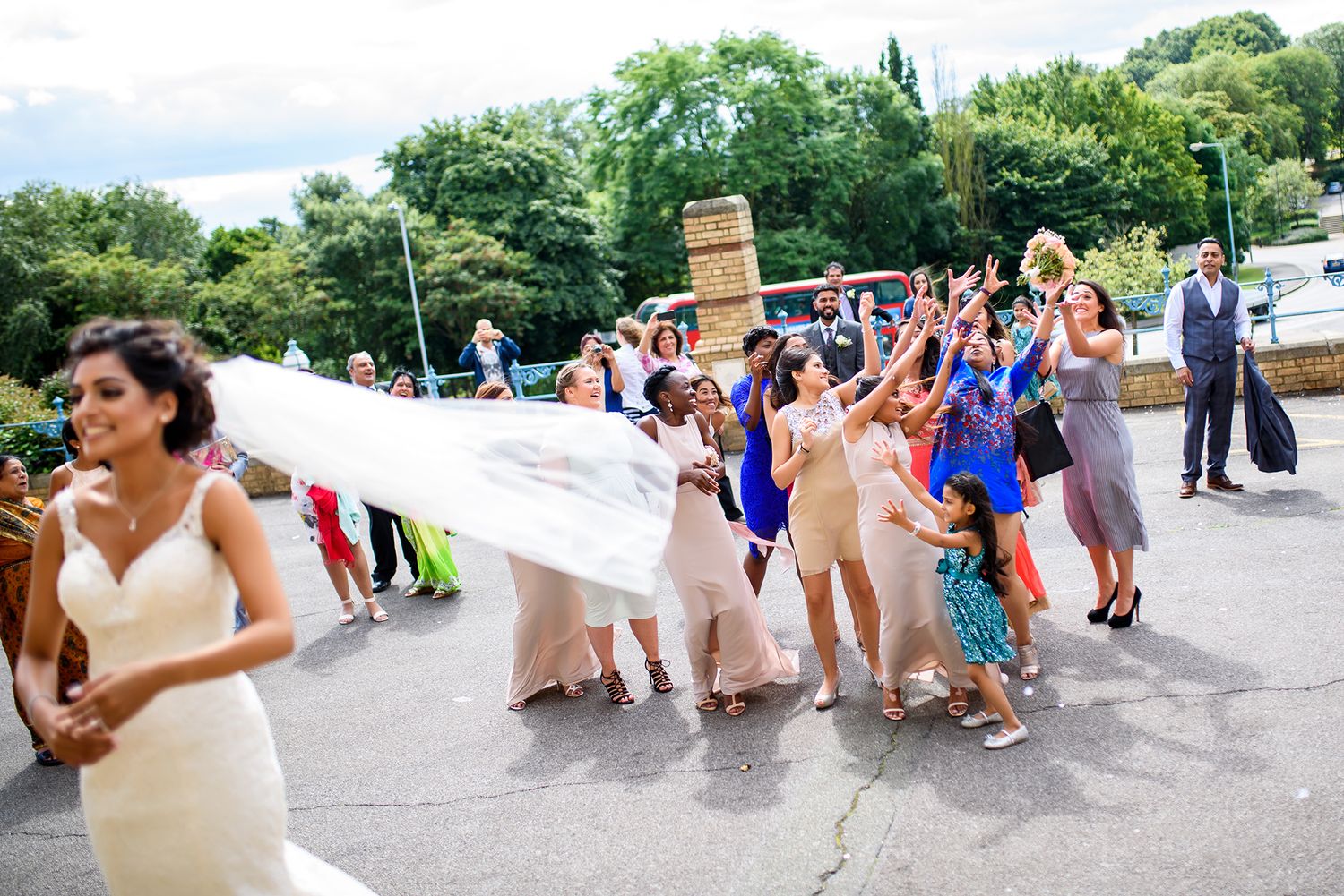 Wide angle view of wedding party and guests celebrating on sunny outdoor terrace.