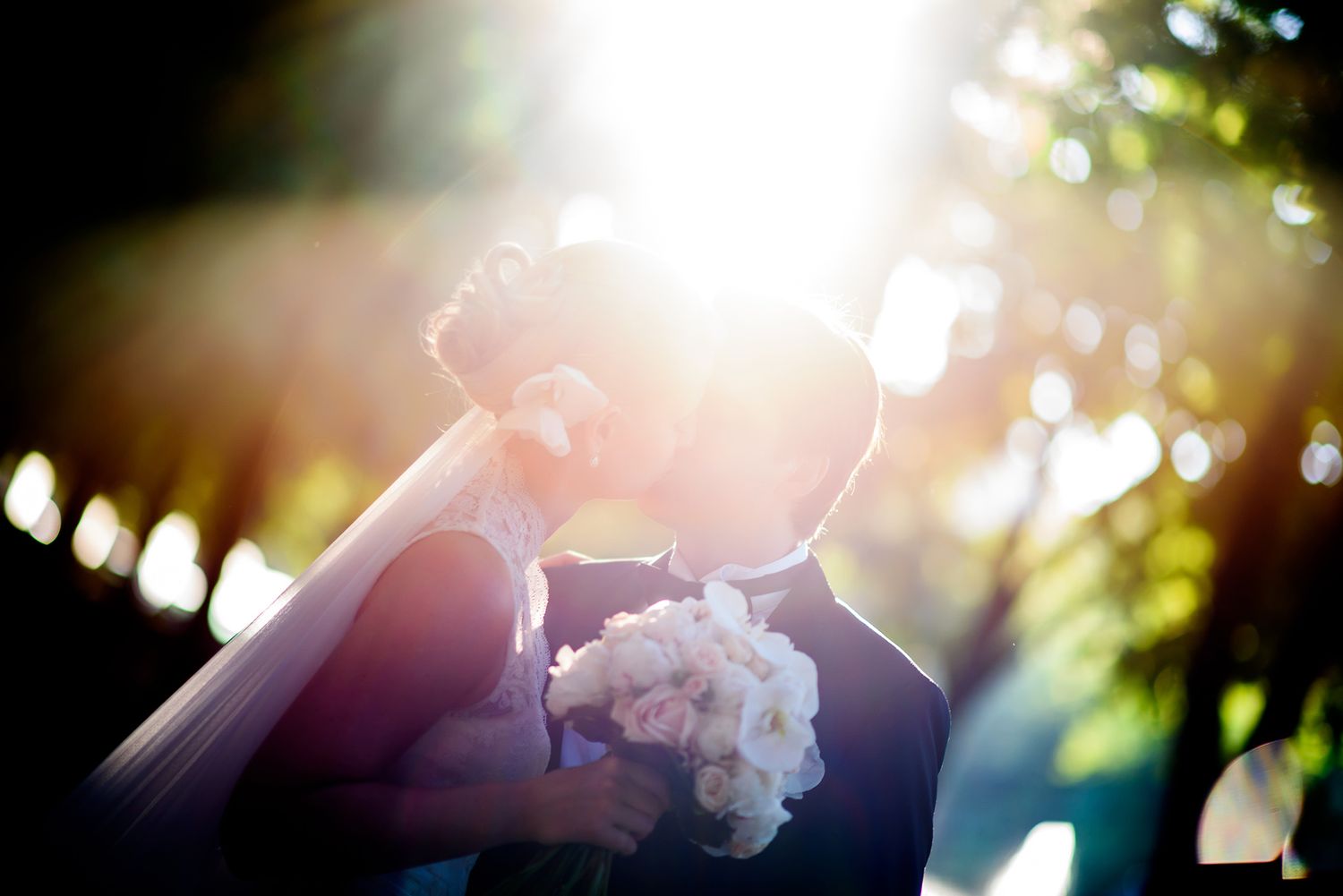 Artistic wedding photograph with natural sunflare through trees.