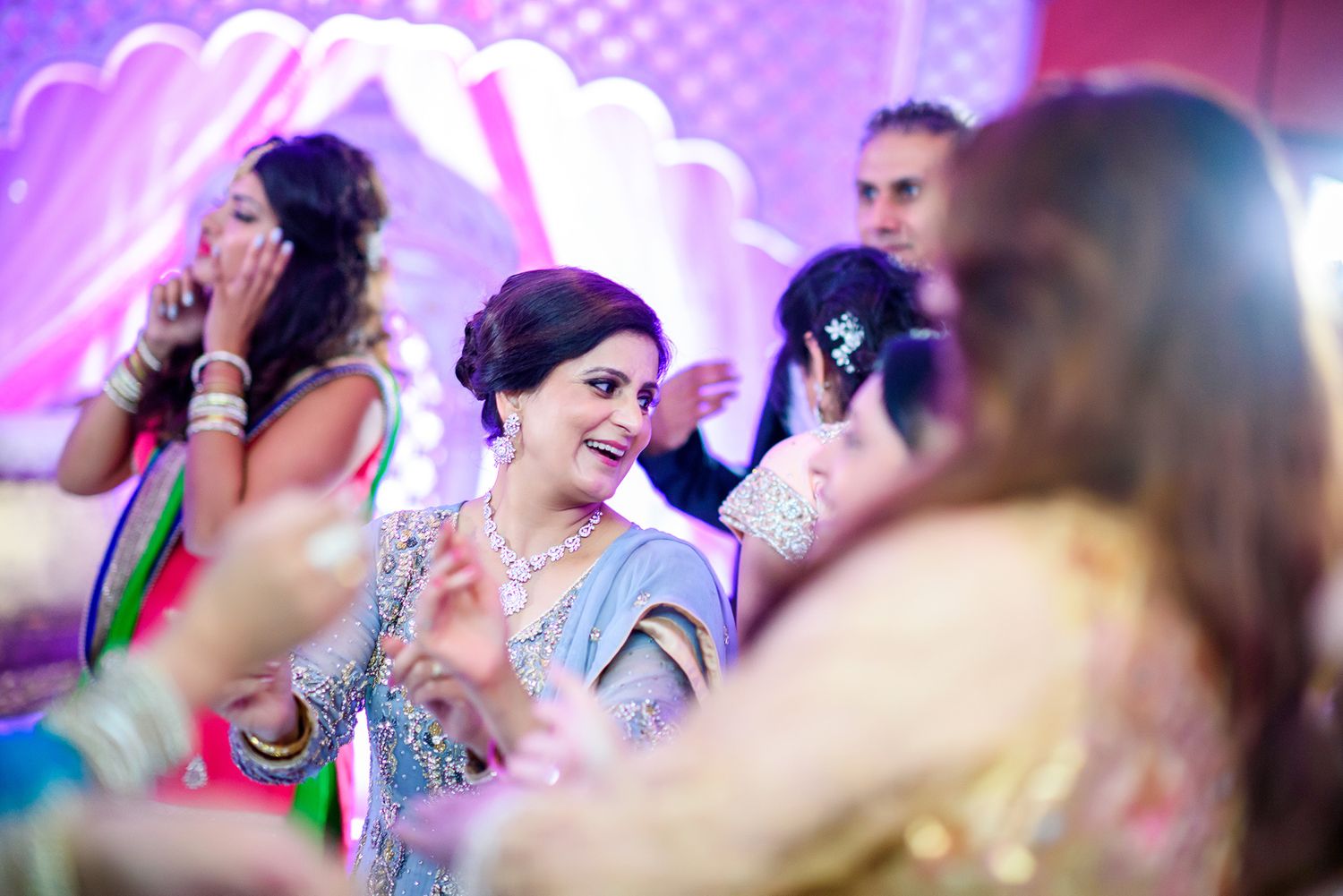 Wedding celebration with purple mood lighting and festive crowd in traditional attire.