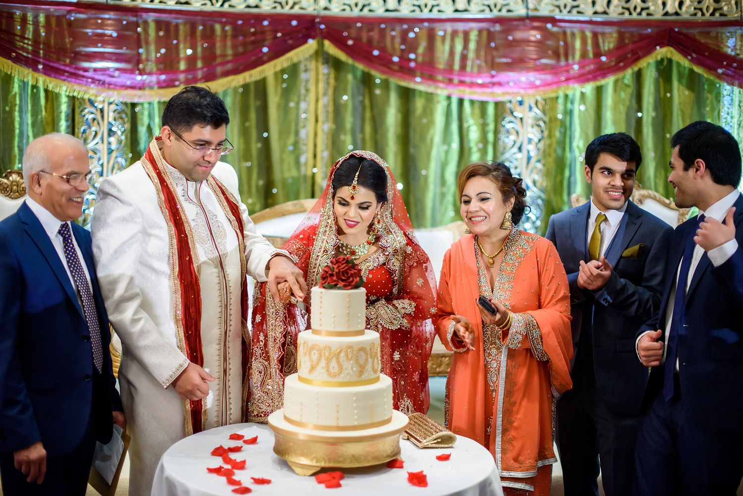 Wedding reception panorama showing guests gathered around decorated cake table.