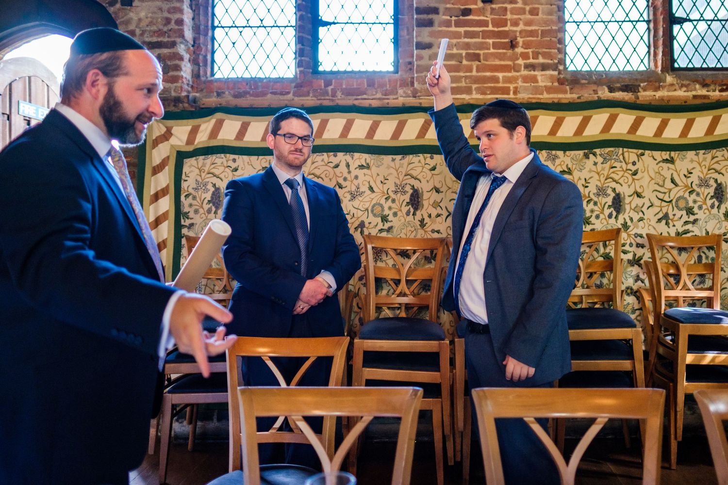 Group gathered in historic brick venue with arched windows and ornate decor.