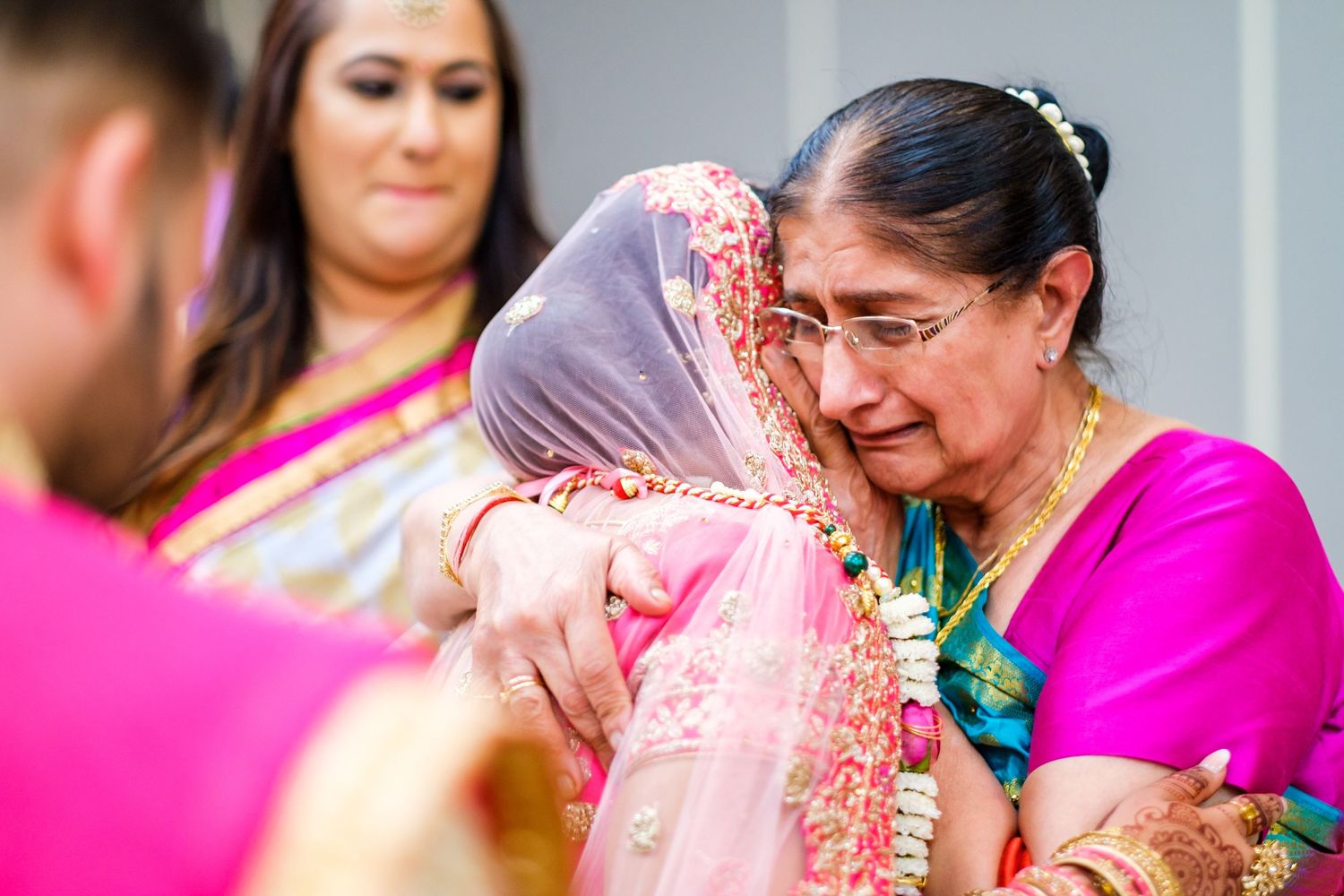 Wedding guests in bright pink and traditional Indian attire gather during celebration.