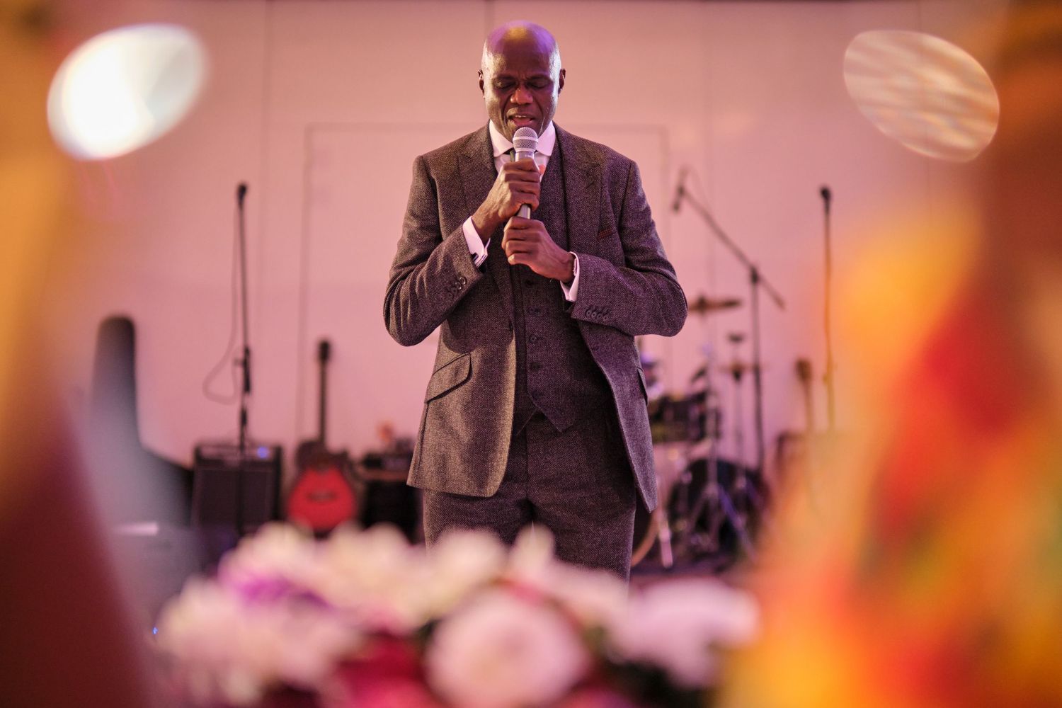 Formal event speaker addressing guests in a warmly lit banquet hall setting.