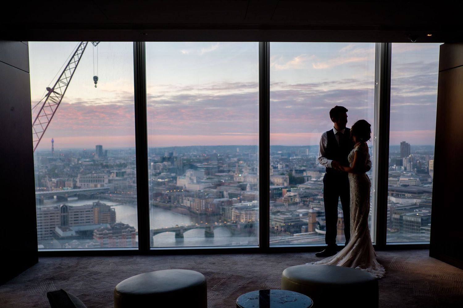 Panoramic cityscape view through floor-to-ceiling windows of a skyscraper at dusk.