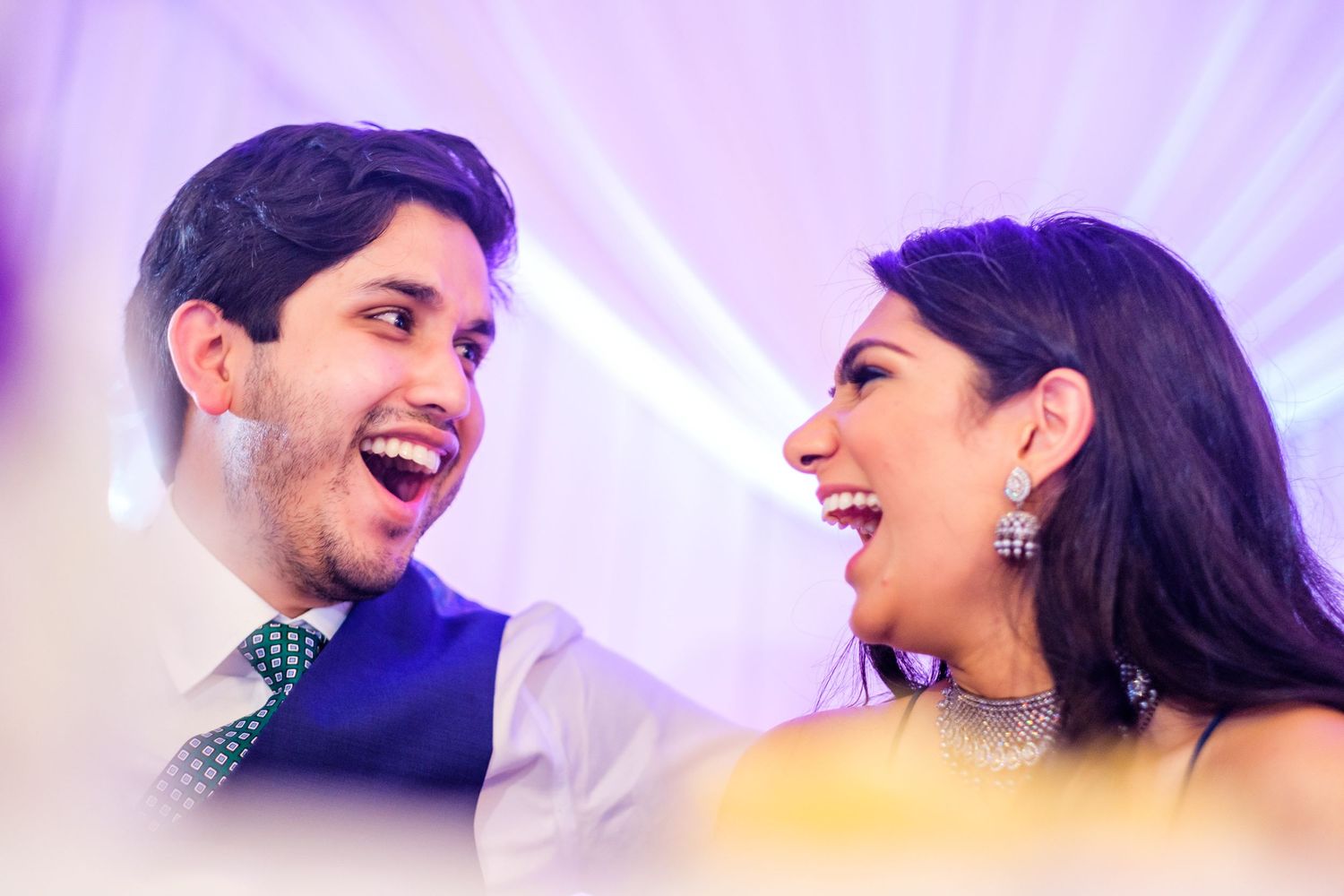 Romantic dance moments captured under purple lighting at an elegant wedding celebration.
