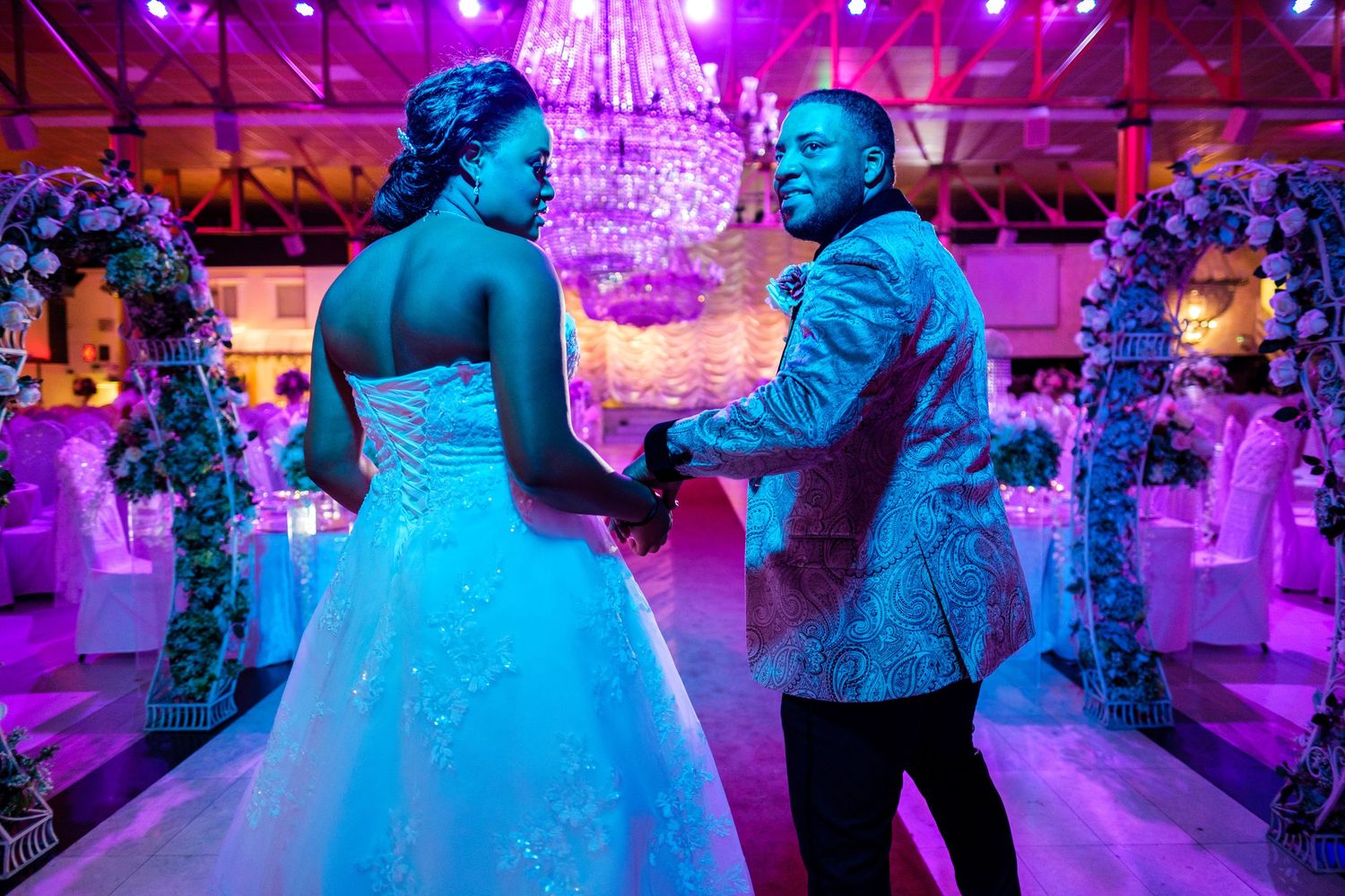 A ballroom dance floor illuminated with vibrant purple and blue lighting creates a romantic atmosphere for dancing.