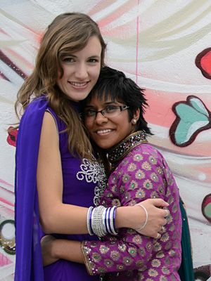 Two friends share heartfelt hug against colorful graffiti wall.