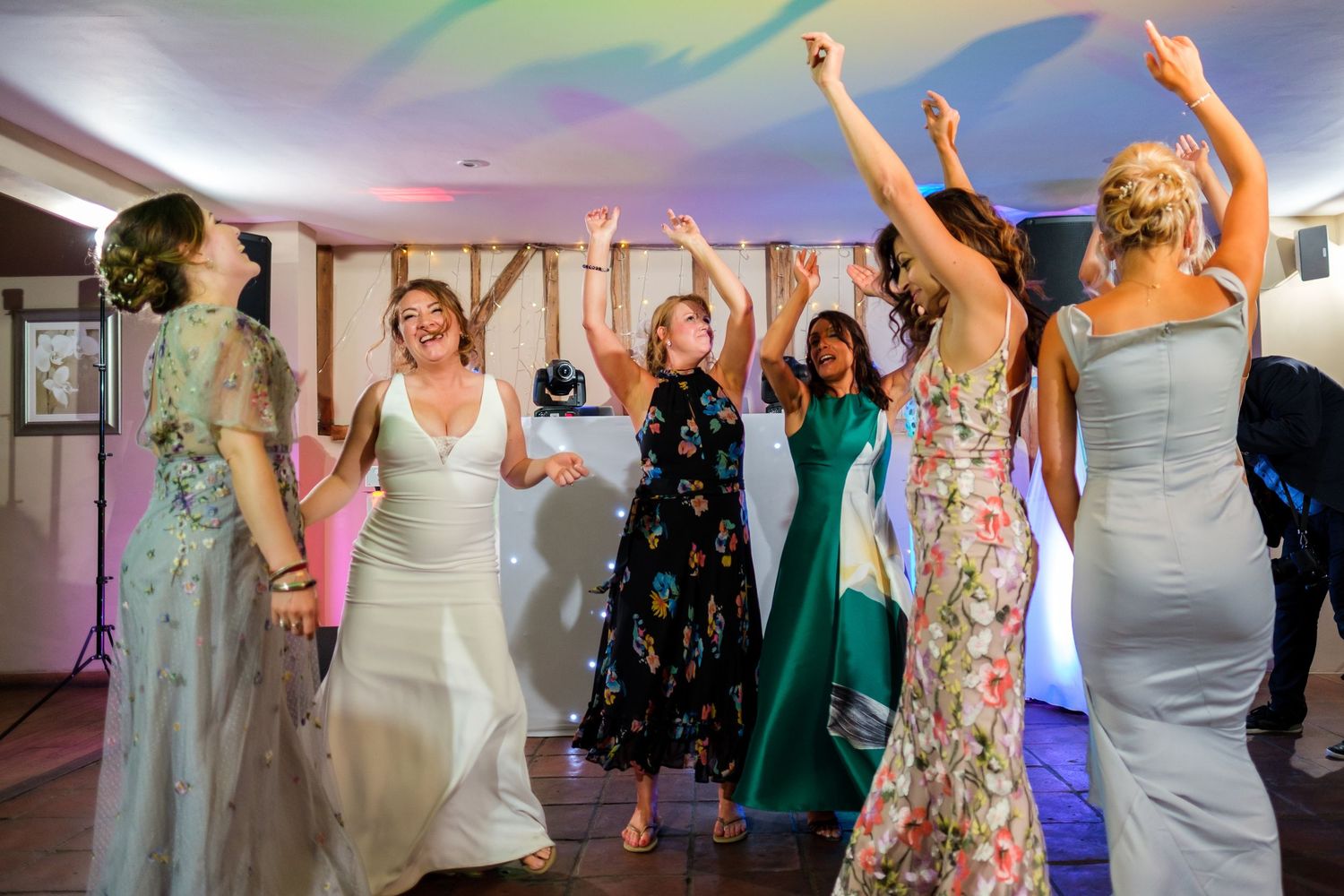 Wedding reception dance floor filled with celebrating guests in colorful attire.