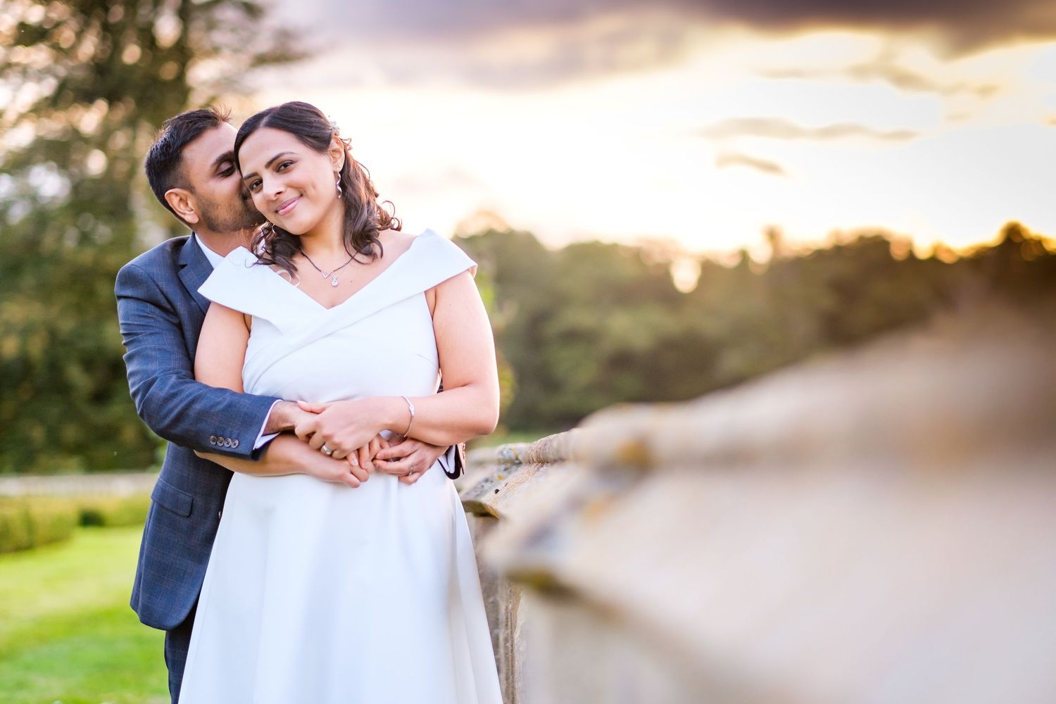 Golden hour portrait session with couple walking along a stone wall at sunset.